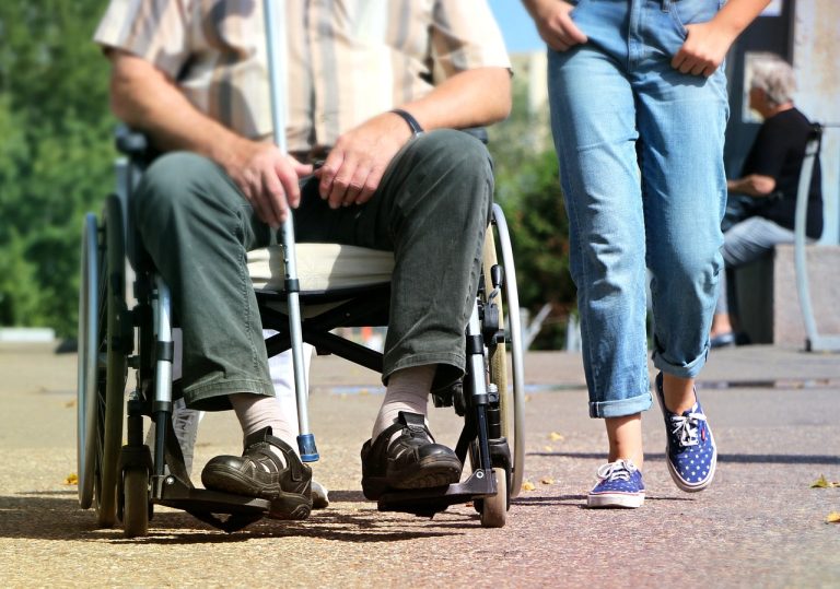 Person i rullstol med ledsagare – symbol för stöd genom LSS personlig assistans och juridisk rådgivning